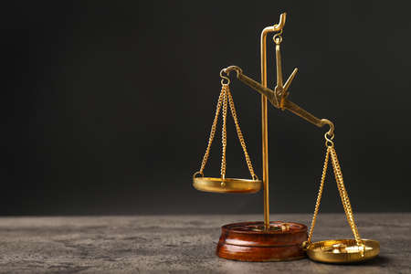 Scales of justice on table against dark backgroundの写真素材