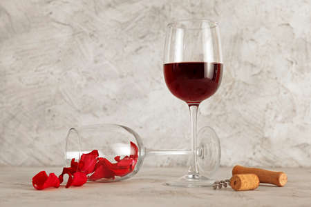 Wineglasses and rose petals on light tableの写真素材