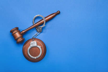 Judge's gavel and handcuffs on color backgroundの写真素材
