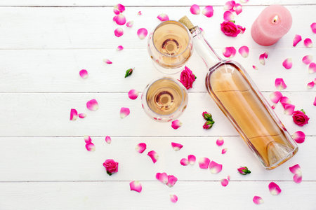 Bottle of wine, glasses, candle and rose petals on tableの写真素材