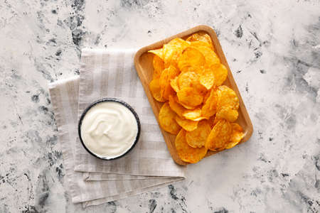 Tasty sour cream and potato chips on tableの写真素材