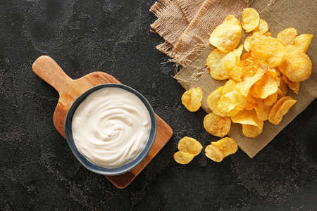 Tasty sour cream and potato chips on tableの写真素材