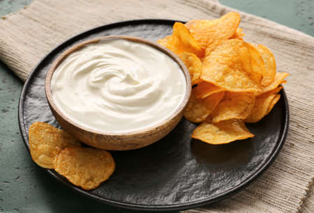 Tasty sour cream and potato chips on tableの写真素材