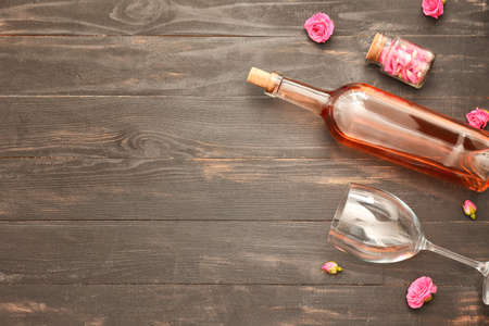 Bottle of wine, glass and rose flowers on tableの写真素材