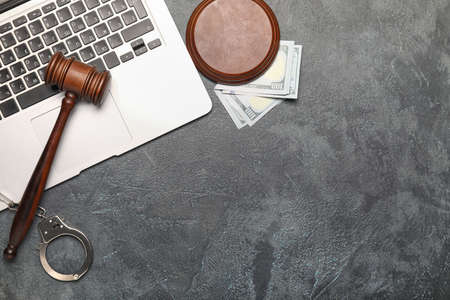 Judge's gavel, laptop, money and handcuffs on gray backgroundの写真素材