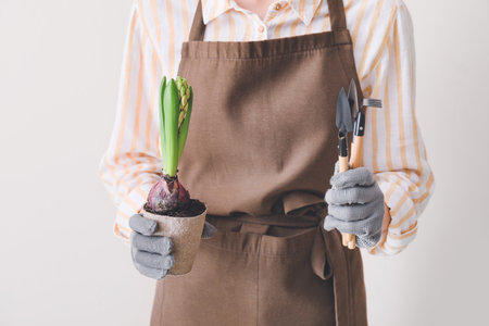 Woman with hyacinth plant and gardening tools on light backgroundの写真素材