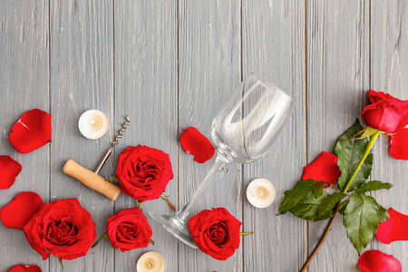 Wine glass with corkscrew, candles and rose flowers on wooden backgroundの写真素材