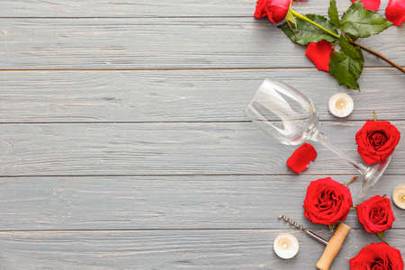 Wine glass with corkscrew, candles and rose flowers on wooden backgroundの写真素材