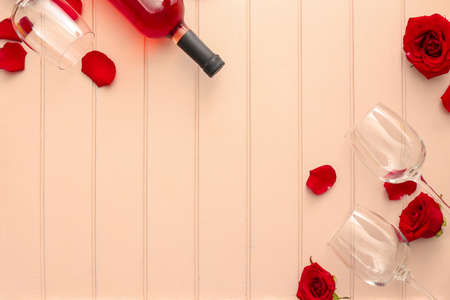 Glasses with bottle of wine and rose flowers on wooden backgroundの写真素材