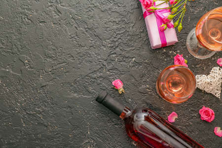Glasses and bottle of wine with gift on dark backgroundの写真素材