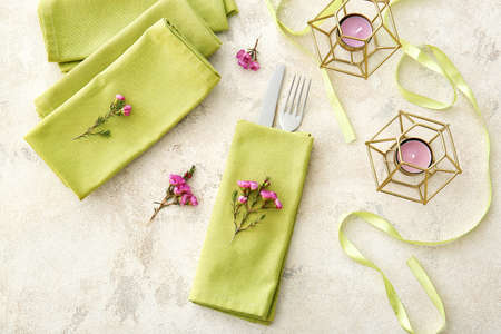 Napkins with cutlery and floral decor prepared for table setting on light backgroundの写真素材
