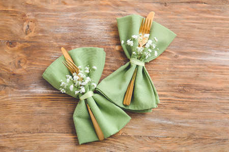 Napkins with cutlery and floral decor prepared for table setting on wooden backgroundの写真素材