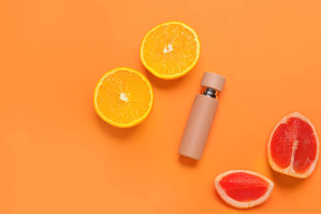 Bottle of perfume with citrus fruits on color backgroundの写真素材