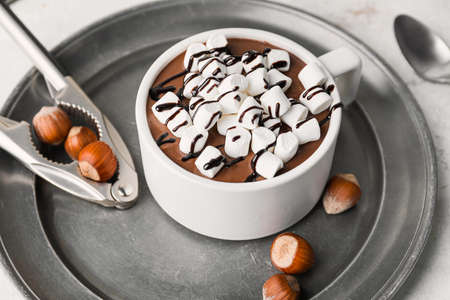 Cup of hot chocolate with marshmallows and hazelnuts on table