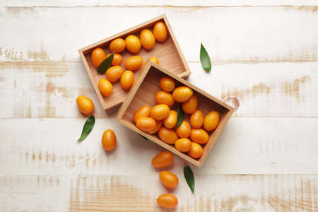 Boxes with tasty kumquat fruit on white wooden backgroundの写真素材