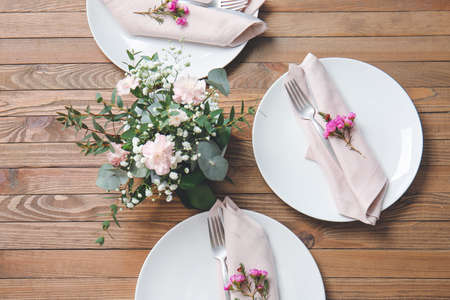 Beautiful table setting with floral decor on wooden backgroundの写真素材
