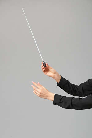 Hands of young female conductor on gray backgroundの写真素材
