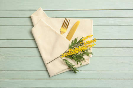 Napkin with cutlery and floral decor on wooden background