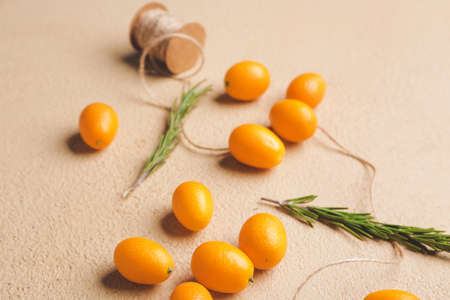 Tasty kumquat fruit with rosemary and thread on color backgroundの写真素材
