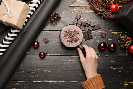 Female hand with cup of hot chocolate and Christmas balls on dark wooden backgroundの写真素材
