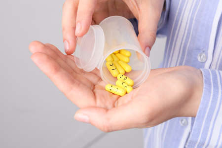Woman holding bottle and pills with drawn faces, closeupの写真素材