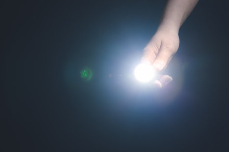Female hand with modern flashlight on dark backgroundの写真素材