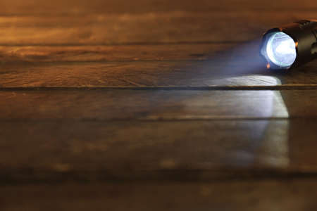 Glowing modern flashlight on wooden tableの写真素材