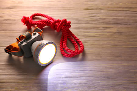 Modern flashlight with rope on wooden backgroundの写真素材