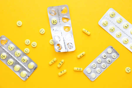 Blister packs and pills with different drawn faces on color backgroundの写真素材