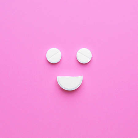 Happy face made of pills on color backgroundの写真素材