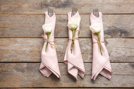 Napkins with floral decor and cutlery on wooden backgroundの写真素材