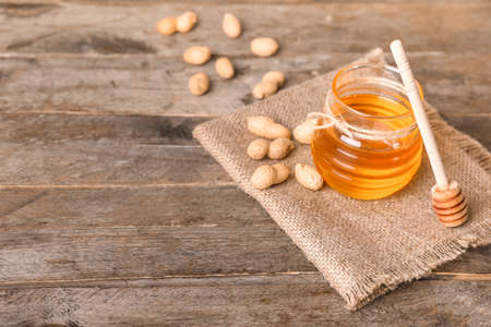 Jar of sweet honey and peanuts on wooden backgroundの写真素材