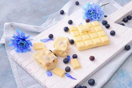 Sweet white chocolate with blueberry and flowers on tableの写真素材