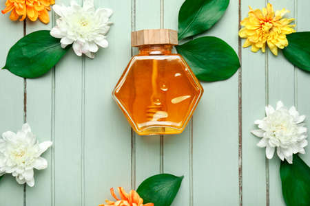 Jar of sweet honey and flowers on wooden backgroundの写真素材