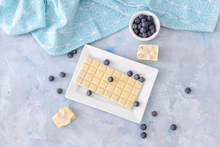 Plate with sweet white chocolate and blueberry on tableの写真素材