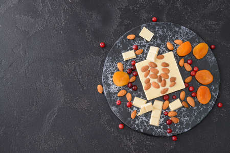 Sweet white chocolate with nuts and dried fruit on tableの写真素材