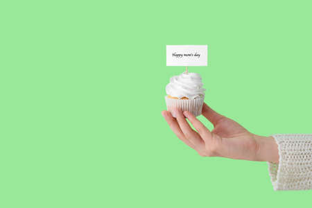 Female hand with tasty cupcake for Mother's Day on color backgroundの写真素材