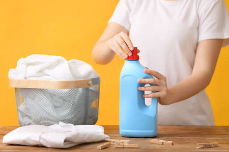 Woman with laundry detergent and clothes on color backgroundの写真素材