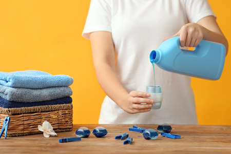 Woman with laundry detergents on color backgroundの写真素材