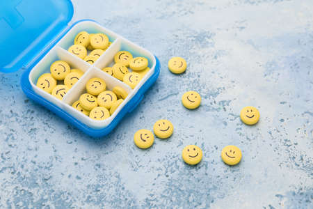 Box and pills with drawn faces on color backgroundの写真素材