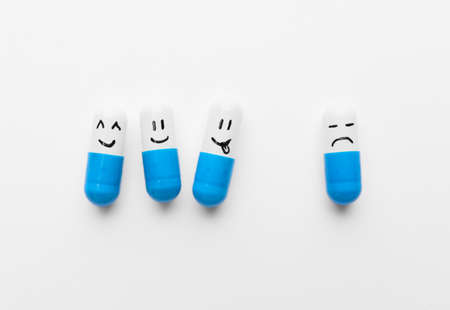 Pills with different drawn faces on white backgroundの写真素材