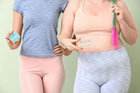 Women with weight loss pills and jumping rope on color backgroundの写真素材