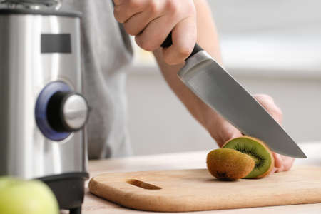 Man cutting fruit for making healthy smoothie at home, closeup