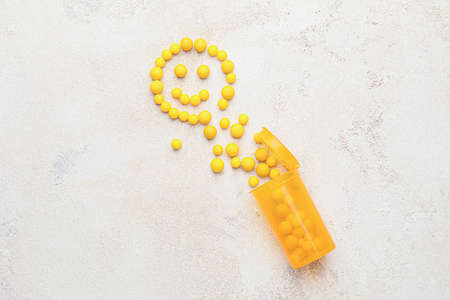 Bottle and face made of pills on gray backgroundの写真素材