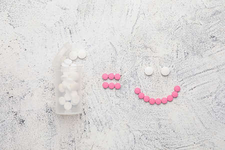 Bottle and face made of pills on gray backgroundの写真素材