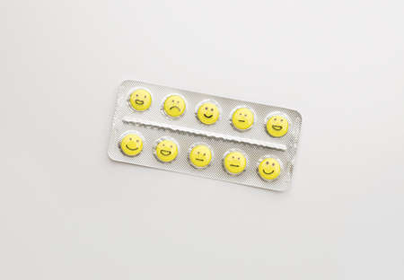 Blister pack and pills with different drawn faces on white backgroundの写真素材