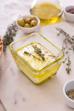 Bowl with tasty feta cheese, oil and spices on tableの写真素材