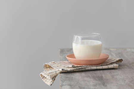 Glass of milk on table against gray backgroundの写真素材