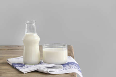 Glass and bottle of milk on table against gray backgroundの写真素材