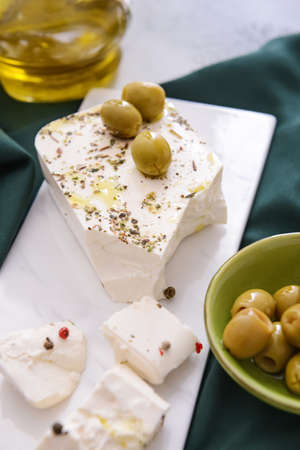 Tasty feta cheese with olives, spices and oil on tableの写真素材